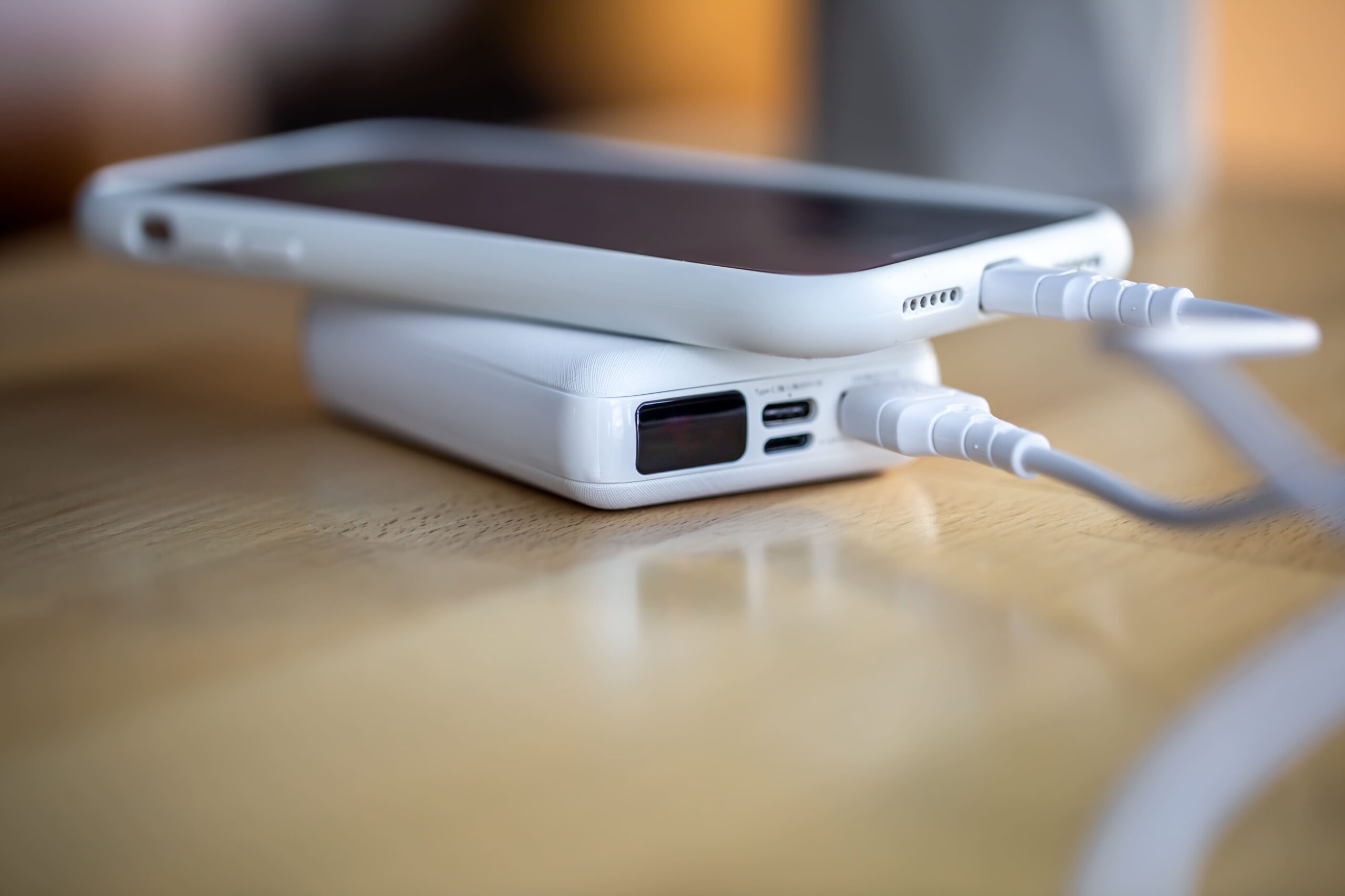 smartphone is charged from small white power bank via cord close up scaled